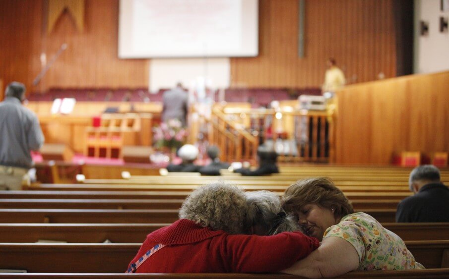 Three women console each other before a memorial service for Oikos University at Allen Temple Baptist Church in Oakland on Tuesday